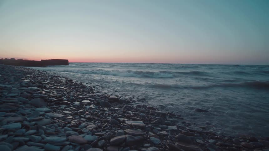 Rocks and stones cover the beach as waves roll in to shore