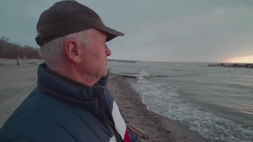 Man in a cap on a beach filming with a smartphone