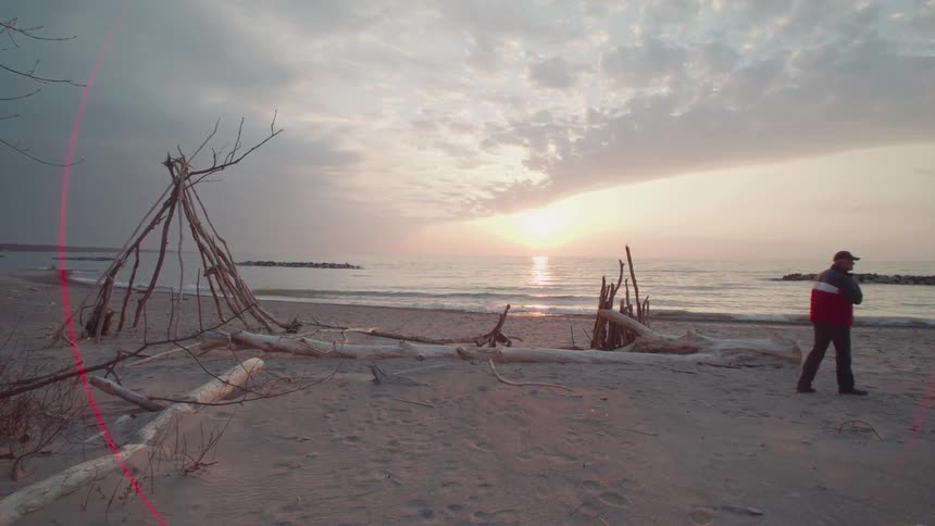 Person in cap walking on a deserted beach at dawn