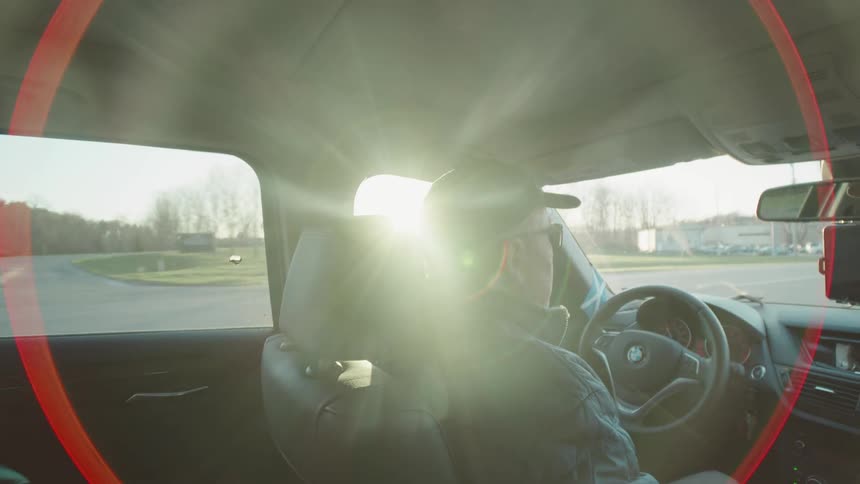 Elderly man in a cap driving a vehicle