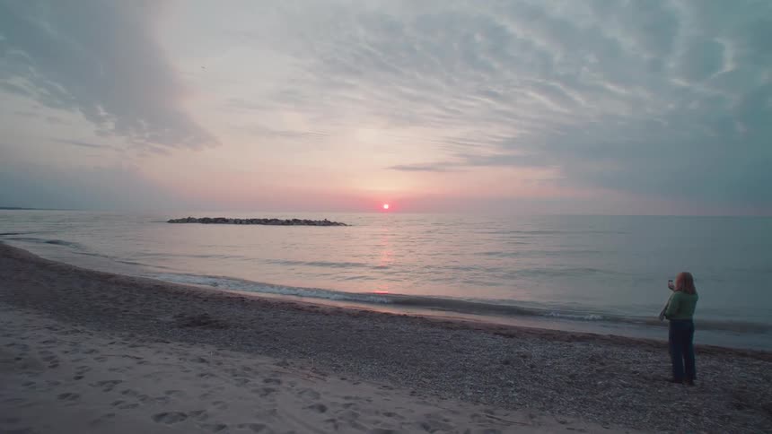 Lonely person enjoying the sunrise on a quiet beach