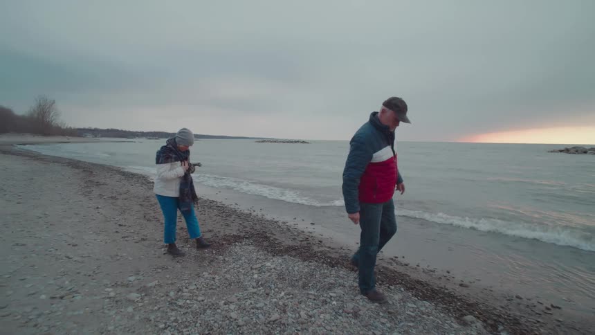 Woman and a man in winter clothes walking on the beach one morning