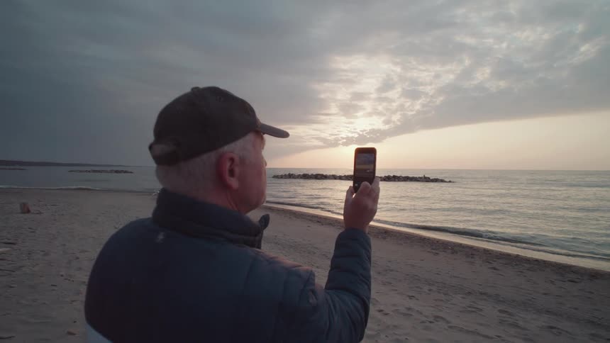 Man wearing a cap with a person filming with his smartphone