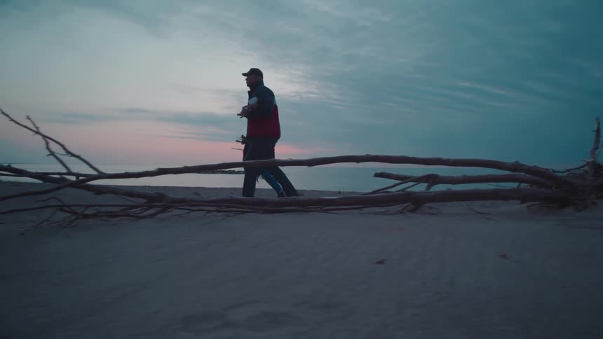 Man and a woman walking along the sand at the seashore on the beach