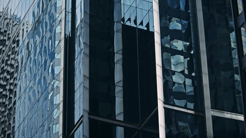 Time lapse of clouds reflecting across the glass of an office tower