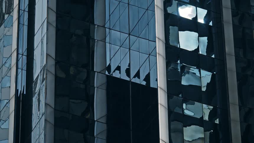 Sunlight & clouds shine off the windows of an office building