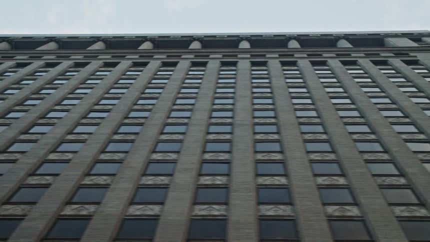 Upward view of a large building with windows and against a cloudy sky