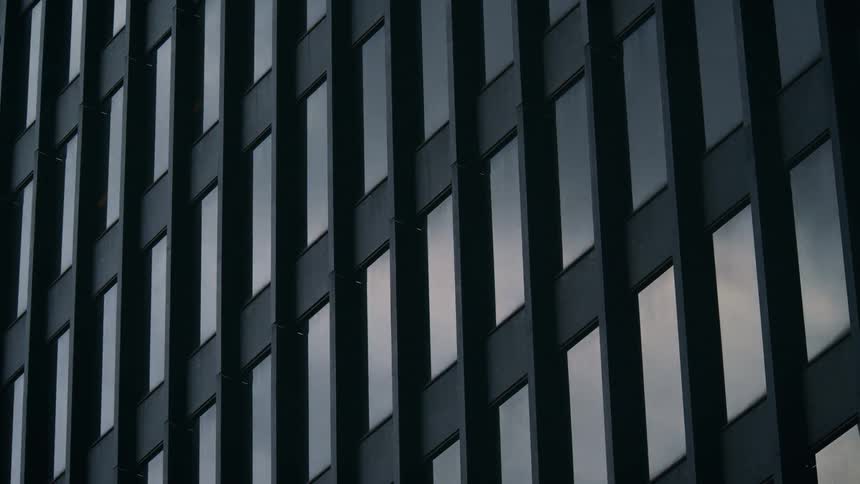 Time lapse of clouds and sunlight reflecting across the windows of an office tower