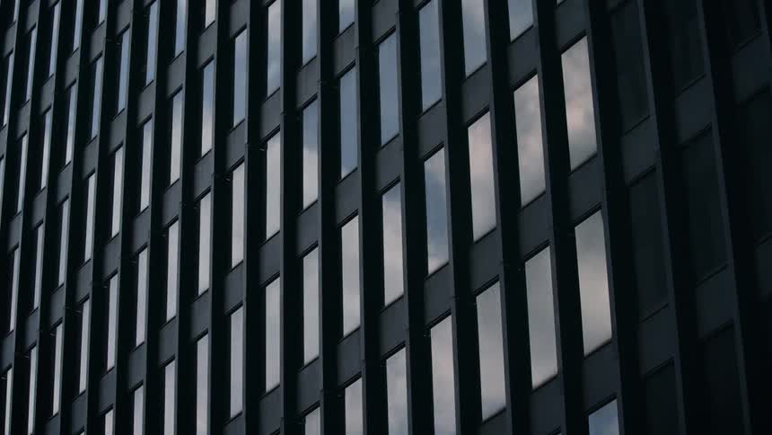 Steel & glass office building reflects clouds rolling by in time lapse