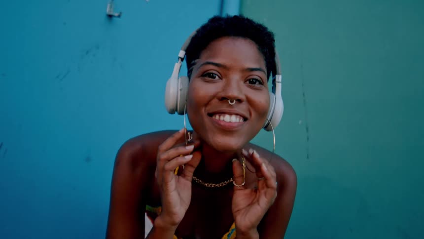 The woman is smiling while listening to music