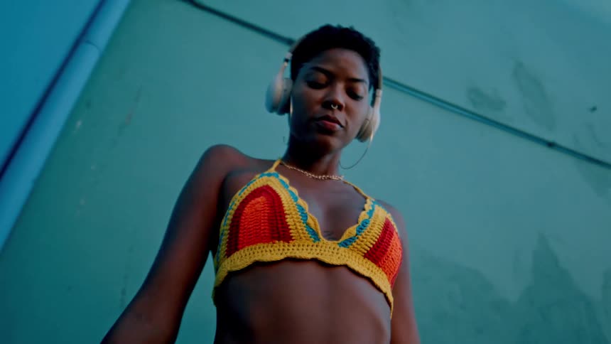 A black girl is dancing wearing headphones outside