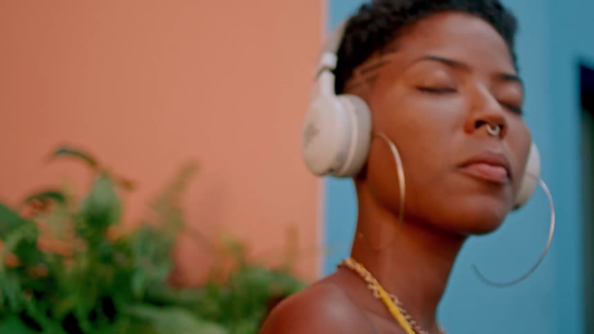 Woman in an outdoor setting with white headphones enjoying the vibe