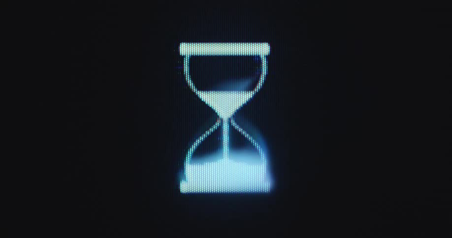 Close up of device screen with RGB or LCD pixels displaying rotating hourglass timer icon from vintage 1990s or nineties windows operating system that takes forever to boot load or start due to slow and low processing power