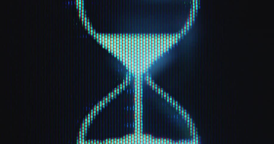 Extreme macro close-up of digital timer displayed on a screen while the sand slowly runs through the hourglass icon or emoji animation as it spins and rotates while glowing in bright white light in front of black computer background