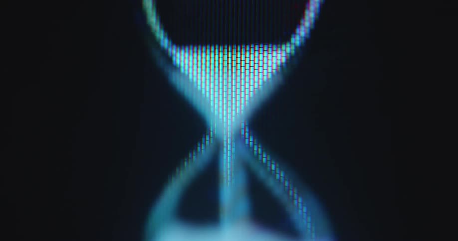 White 2D animated pixel art hourglass icon rotates on a black pixelated computer screen as the sand is dripping and the waiting time is running out while the computer program or user interface is loading