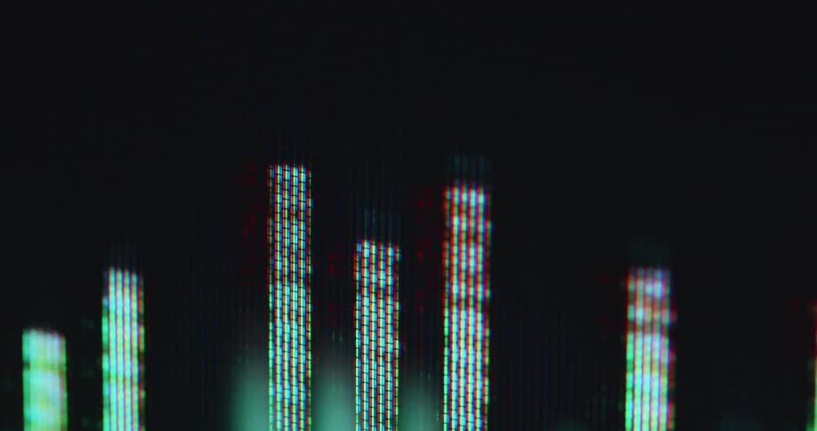 Hand held macro close up of the pixelated RGB screen of an electronic device or vintage tube TV displaying a green equalizer animation with red tips as the music or podcast is being played by an audio player app or software