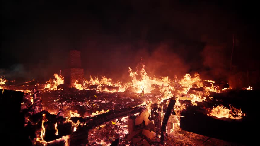 Burneddown building with fire still burning through wood and debris