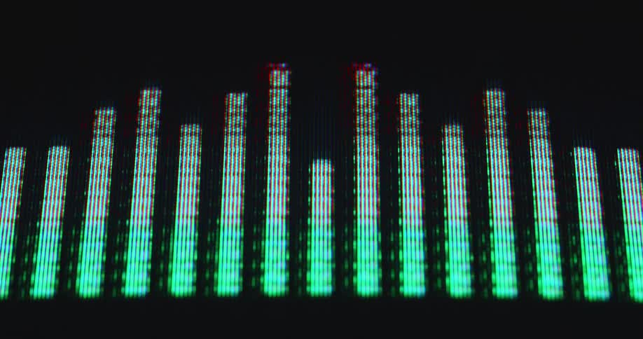 Screen of a vintage stereo system or Hi-Fi device displaying music graphs or EQ bars in green colors with red tips visualizing the sound and waveform of the audio track being played on an online streaming platform