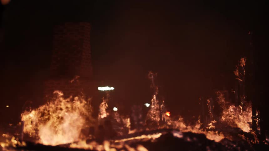 Chimney stands in the remains of a burning house at night