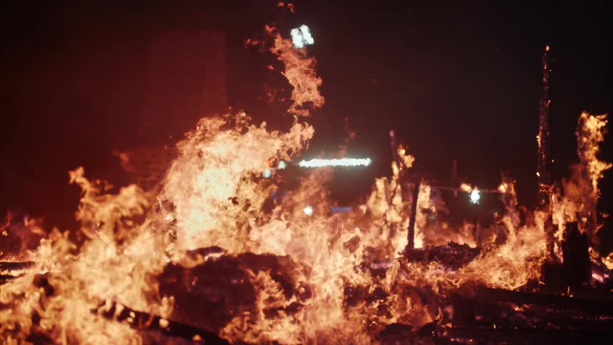Structure of a house burning down engulfed in flames at night