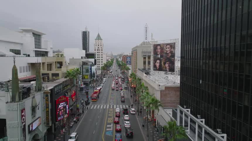 Busy Hollywood Boulevard with cars buildings and people under a cloudy sky