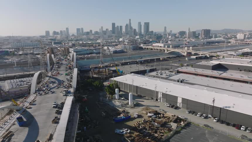 Aerial view of an underconstruction bridge with the city skyline in the background