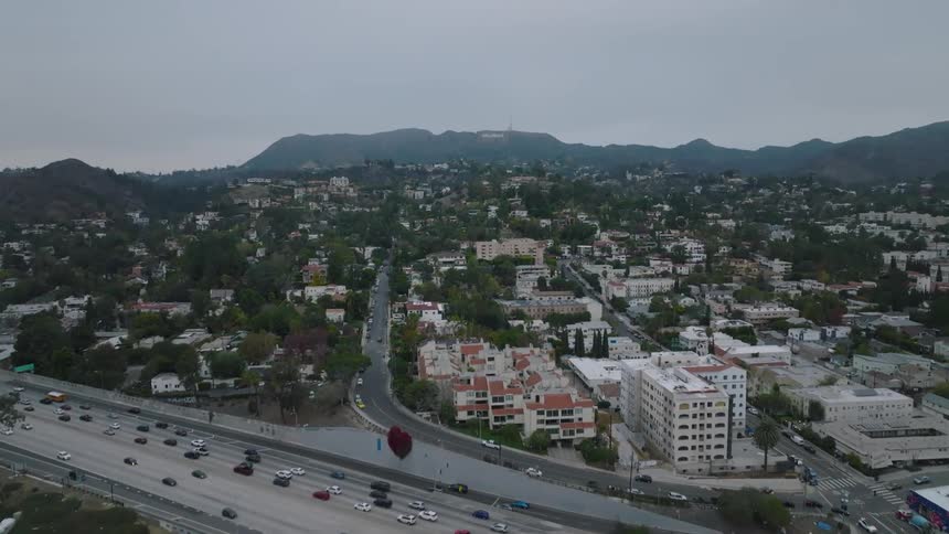 Traffic moves on a highway through a city that has a lot of trees