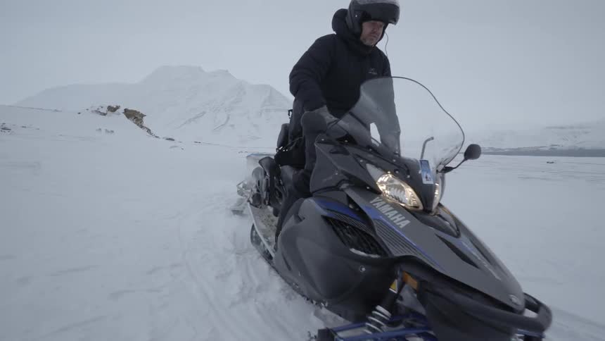 A man rides by dragging equipment in a snow ski