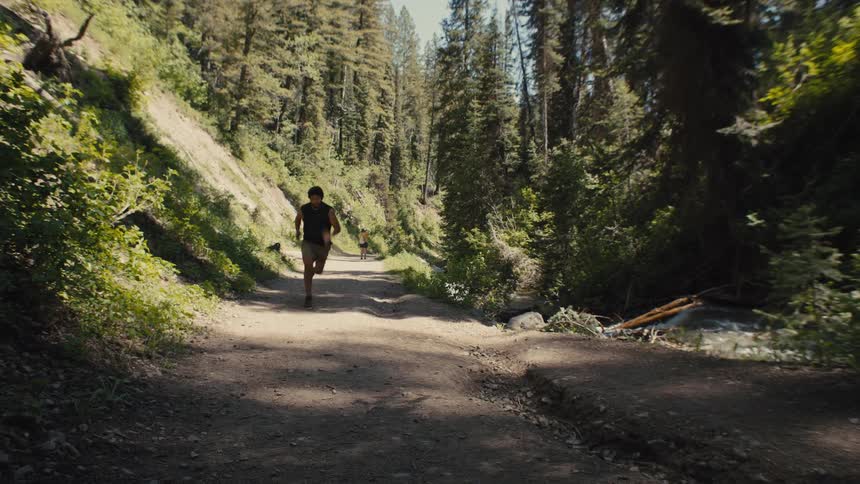 A male is running fast down a trail in the woods