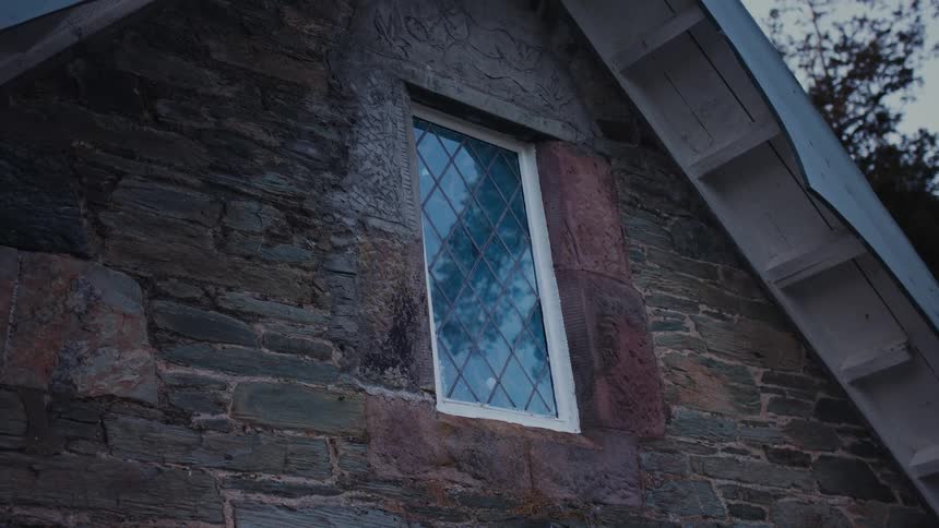 A single window is on the side of the stone home