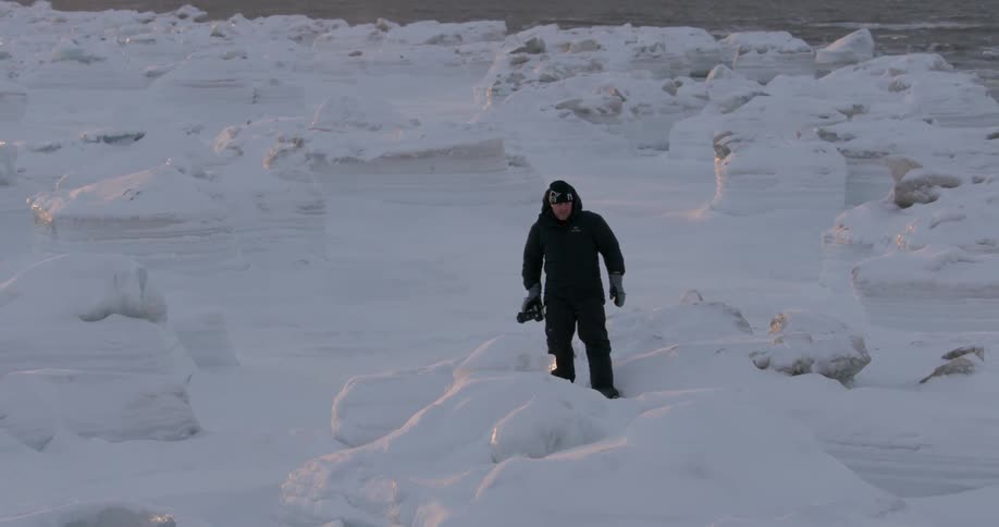 A man hikes along the snow and ice filled shore