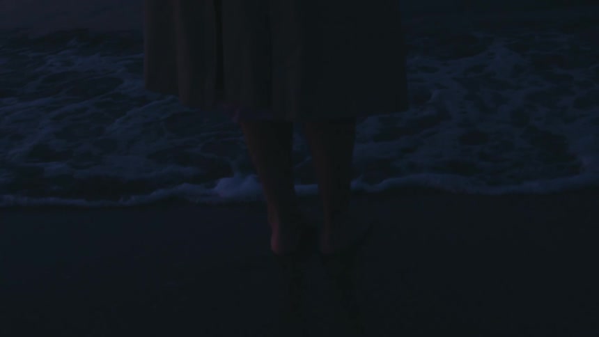 Legs of a person walking on calm waters on a dark dawn