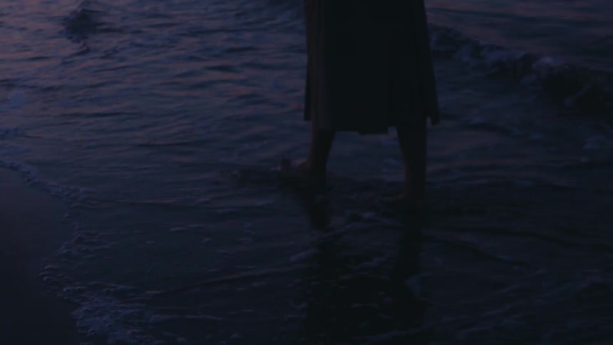The woman leaves footprints in the sand as she walks