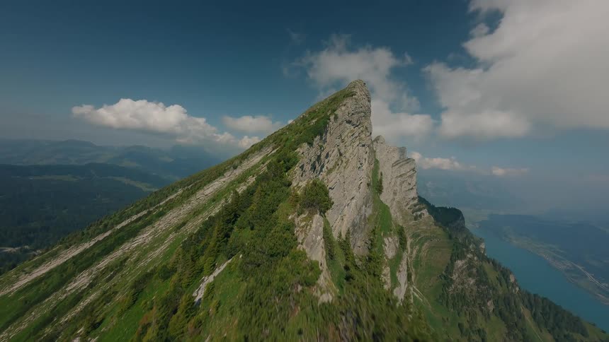Drone Clip of a Steep Mountain Ridge Ending at a Cliff Overlooking a Lake on a Foggy Day