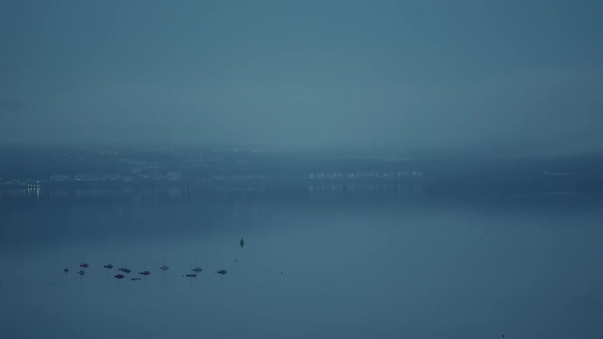 Silhouette of boats in a sea with a city in the background