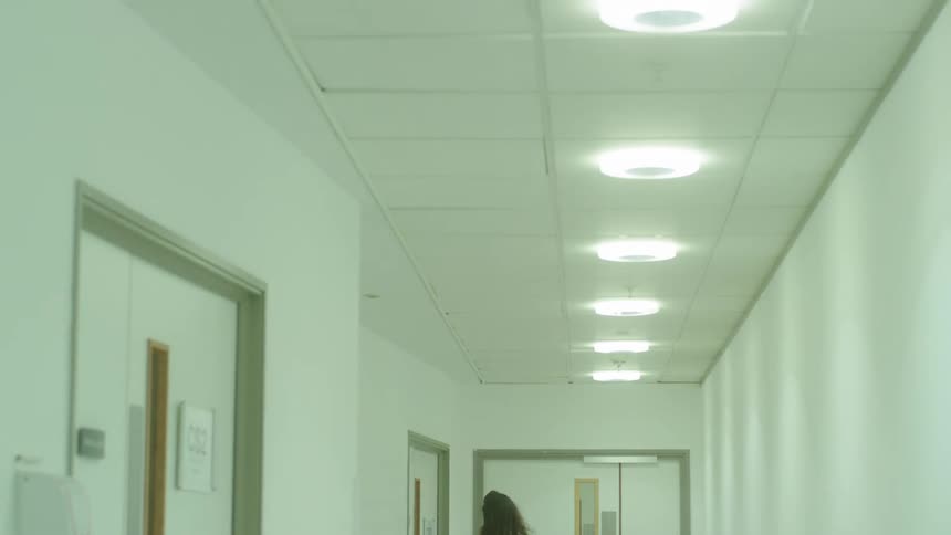 Woman walking down a bright hallway