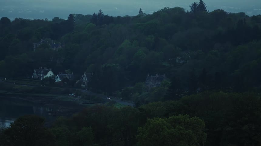 A quiet forested rural neighborhood is captured at dusk with soft dim lighting