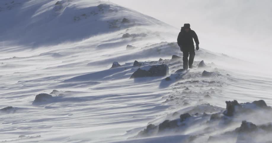 Snow blows across the air as a man treks through it