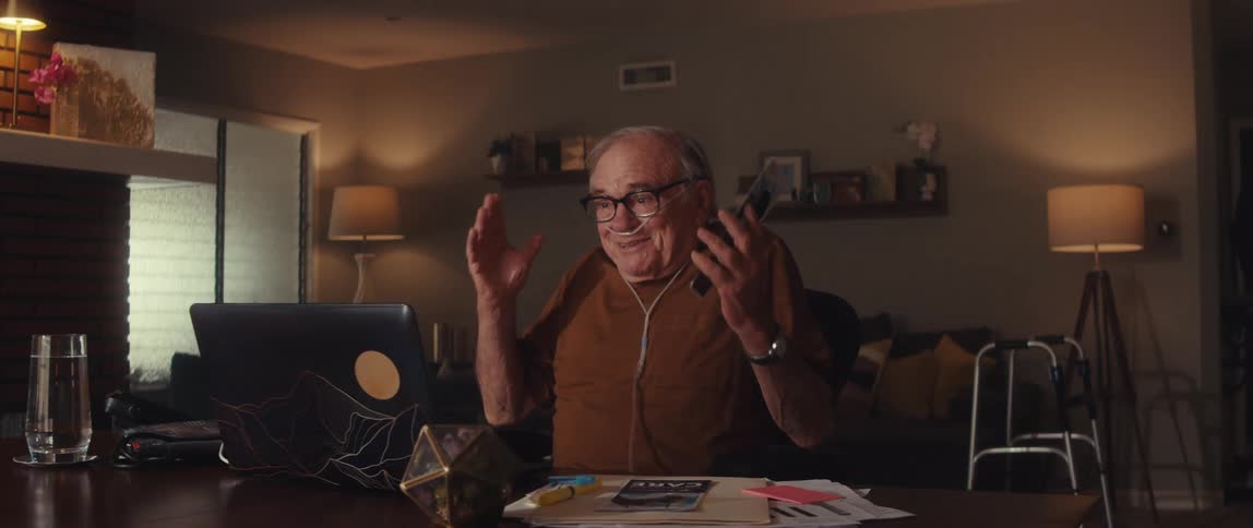 An elderly man enjoys a joyful video call at his desk