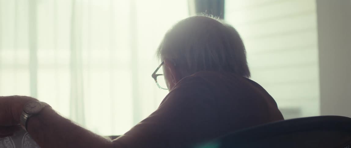 An elderly man has a video call with a female doctor while reviewing medical scans