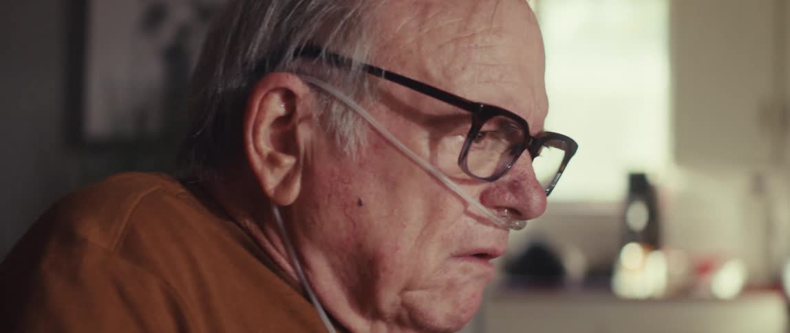 A man with a oxygen tube is talking at home