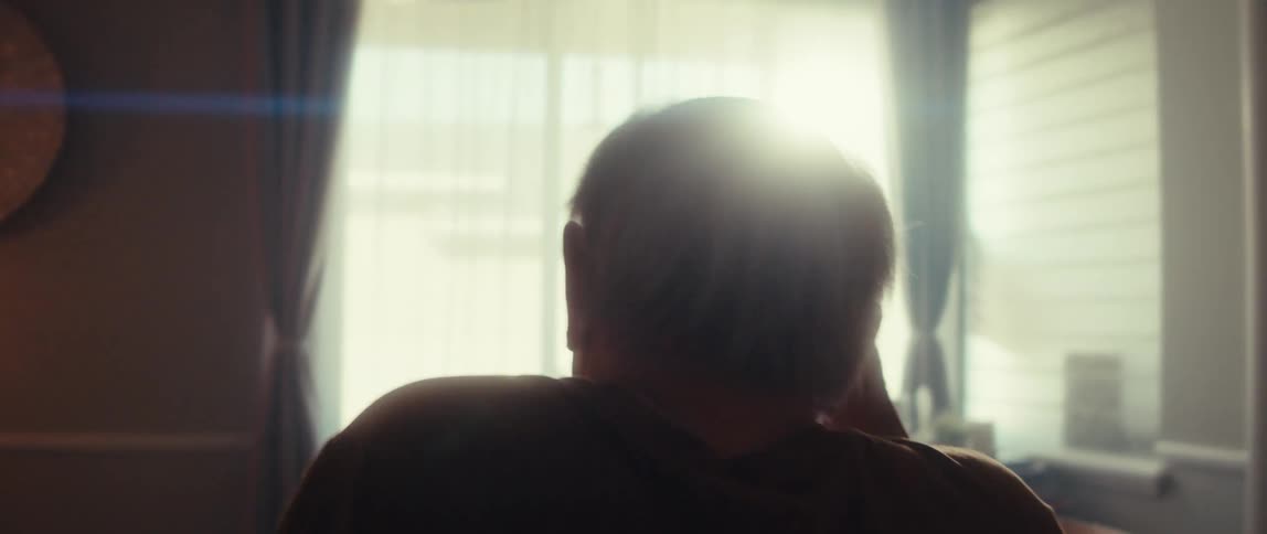 An elderly man speaks to a doctor on a video call in a cozy room