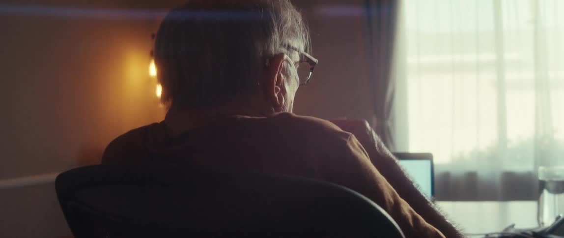 The man is waving his hands while talking with someone on a video call
