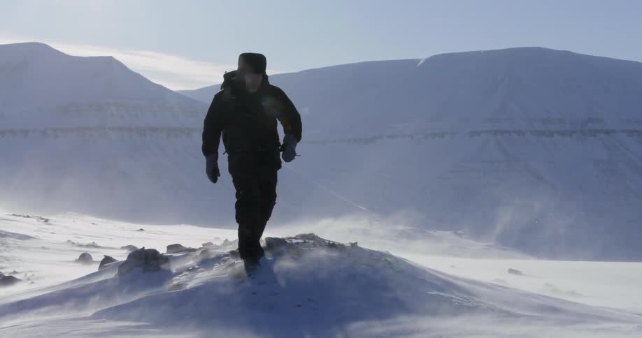 A man walks up a snowy hill