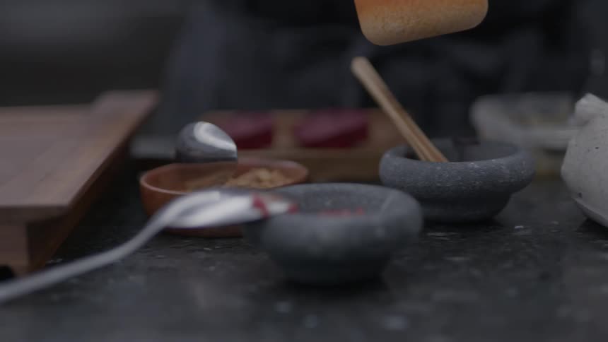 A chief spoons sauce in the kitchen