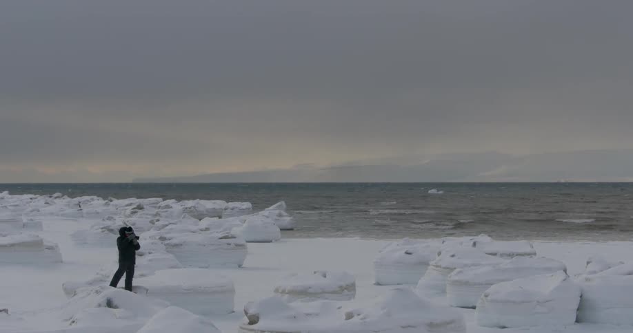 A man photographs the shore on a cloudy day