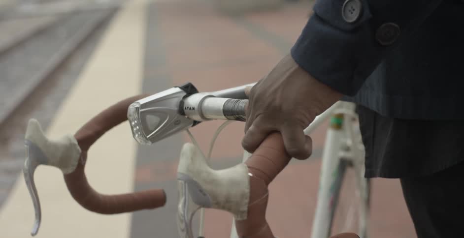 A person stands holding a bike