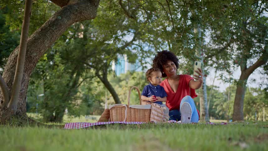 A mother and daughter take are taking a selfie while having a picnic