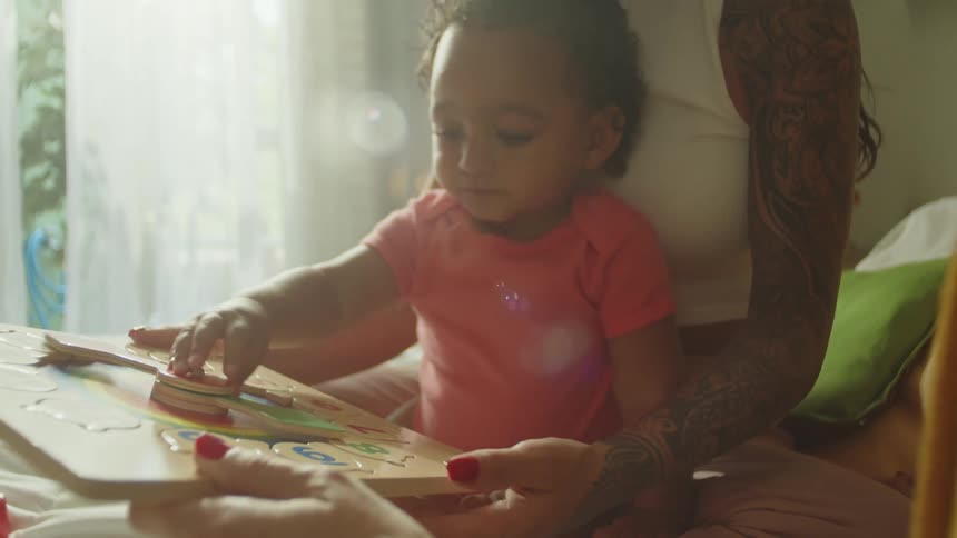 Little girl playing with toys and accompanied by two women