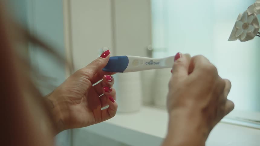 Pair of womans hands holding a pregnancy test